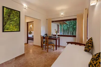a bedroom with a bed and a desk and a table at Sterling Vythiri Wayanad in Wayanad