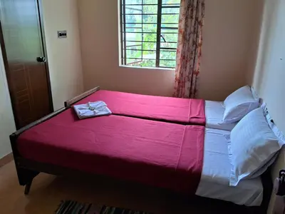 a bedroom with a bed with a pink blanket on it at Homely Homestay in Kalpetta