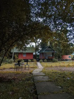 a park with two benches and a table and a building at The Wayanad Club in Sultan Bathery