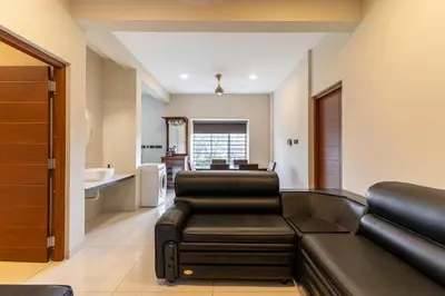 a living room with a black leather couch and chairs at Amminis Mansion by Doris Homes in Trichūr
