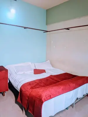 a bedroom with a bed with a red blanket at VKR MENS ROOM (Gents Only) in Kozhikode