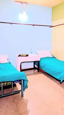 a room with two beds and a table in it at VKR MENS ROOM (Gents Only) in Kozhikode