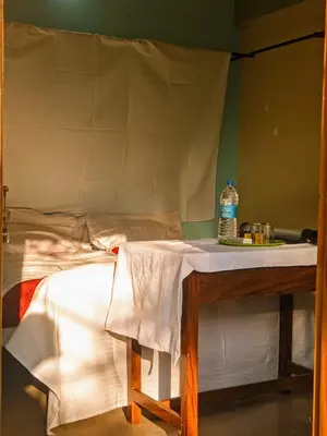 a bed with a table with a bottle of water on it at VKR MENS ROOM (Gents Only) in Kozhikode