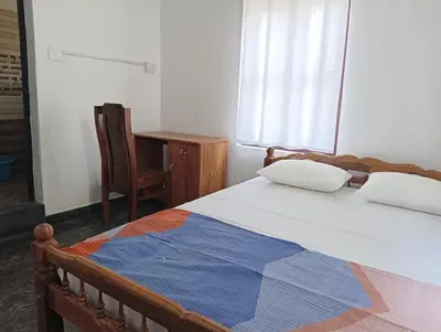a bedroom with a bed and a chair and a window at BHASURI VILLA Attappady in Varagampadi
