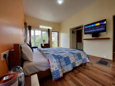 a bedroom with a bed and a flat screen tv at Serenity inn - Rose Garden in Ooty