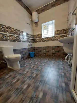 a bathroom with a toilet and two sinks and a window at Serenity inn - Rose Garden in Ooty