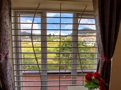 a window with a view of a field at Serenity inn - Rose Garden in Ooty