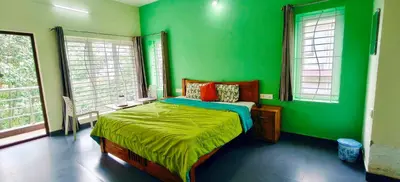 a green bedroom with a bed in a room with windows at Serenity inn - Rose Garden in Ooty