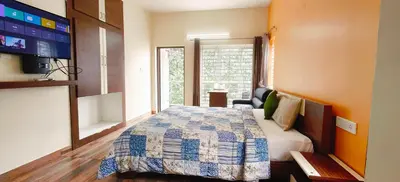 a bedroom with a bed and a tv in it at Serenity inn - Rose Garden in Ooty