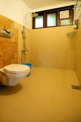 a bathroom with a toilet and a shower at Solitude Munnar - Tree house in Munnar