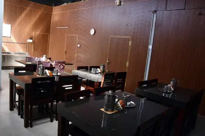 a restaurant with tables and chairs and a clock on the wall at Vanam Holidays in Ooty