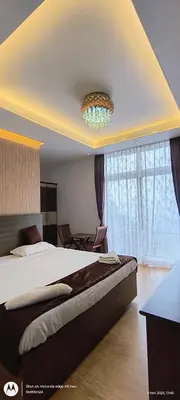 a bedroom with a large bed and a chandelier at Vanam Holidays in Ooty