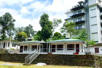 a house in front of a tall building at Mountain View cottage Mankulam in Munnar