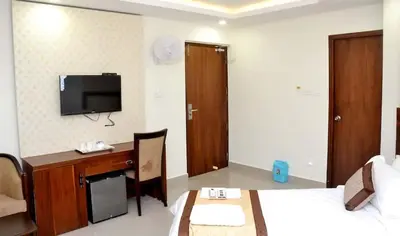 a hotel room with a desk and a tv on the wall at Rotano Glitz Inn - Glitz Inn Calicut in Kozhikode