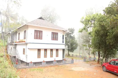a white house with a red car parked in front of it at The Lavender Woods in Vythiri
