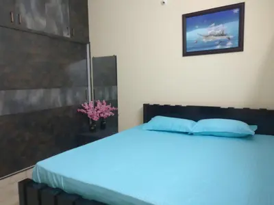 a bedroom with a blue bed with a picture on the wall at SindooRa in Mysore