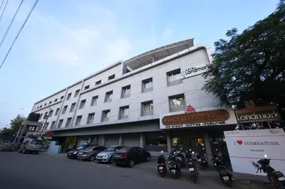 a large white building with motorcycles parked in front of it at Hotel LandmarK Coimbatore in Coimbatore