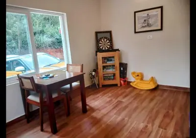 a living room with a dining room table and a dog toy at Sleeping Beauty by Nature Resorts and Stays in Coonoor