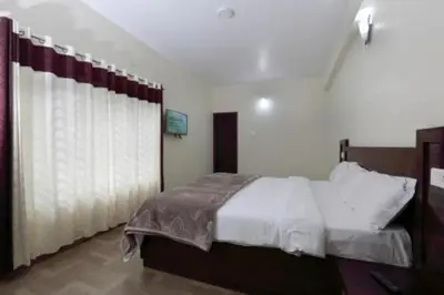 a bedroom with a large bed and a curtain at Pinehill Suites in Ooty