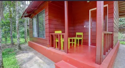 a red house with two chairs and a table on the porch at Lazo Areca Resort , Coorg in Madikeri