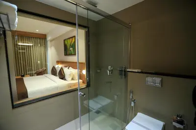 a bathroom with a shower and a bedroom with a bed at Hotel Saffron Wayanad in Sultan Bathery
