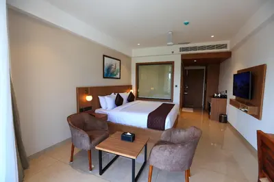 a hotel room with a bed and a table and chairs at Hotel Saffron Wayanad in Sultan Bathery
