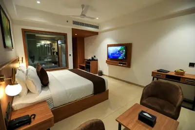 a hotel room with a bed and a tv at Hotel Saffron Wayanad in Sultan Bathery