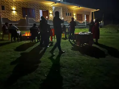 a group of people standing in front of a fire at night at REHMANS HOMESTAY in Ooty