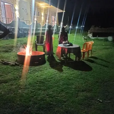 a group of people standing around a fire in a yard at REHMANS HOMESTAY in Ooty