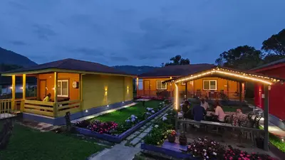 a house with people sitting at a table in the yard at The Laughing Woods AC Resort in Kotagiri