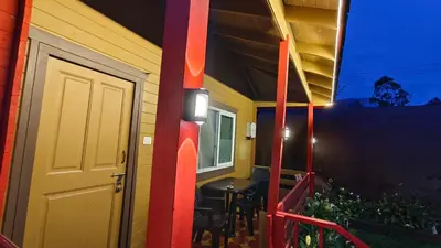 a porch of a house with a table and a door at The Laughing Woods AC Resort in Kotagiri