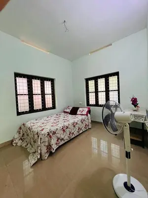 a bedroom with a bed with a fan and windows at Ocean Pearl in Kozhikode