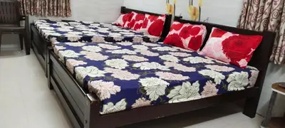 a bed with a blue and white quilt and red pillows at SAMPATH RESIDENCY in Palani