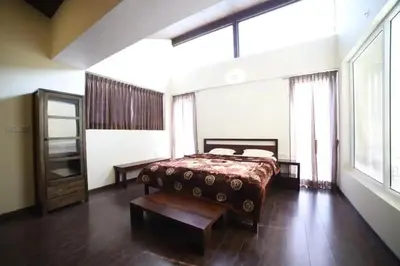 a bedroom with a bed and a large window at DWELLINGTON in Kotagiri