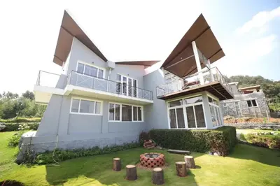 a large white house with a large yard at DWELLINGTON in Kotagiri