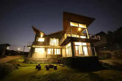 a large house at night with its lights on at DWELLINGTON in Kotagiri