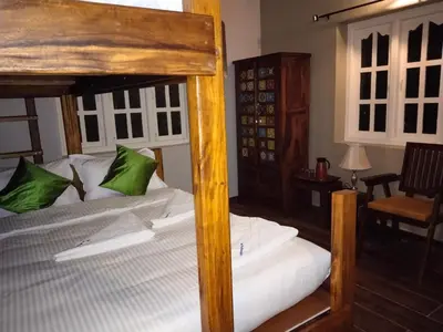 a bedroom with a large wooden bed with green pillows at INN THE MOUNTAIN'S in Kodaikānāl