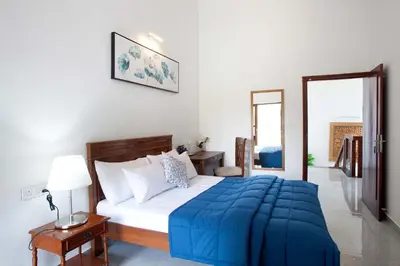 a bedroom with a bed with a blue blanket on it at StayVista at Ivory Hill Madikeri including breakfast 3 Bhk Villa in Madikeri