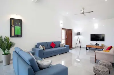 a living room with blue couches and a tv at StayVista at Ivory Hill Madikeri including breakfast 3 Bhk Villa in Madikeri