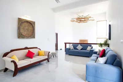 a living room with two couches and a chandelier at StayVista at Ivory Hill Madikeri including breakfast 3 Bhk Villa in Madikeri