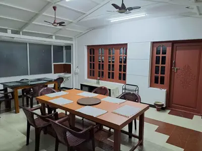 a dining room with a table and chairs in a room at Blossom Inn in Coonoor